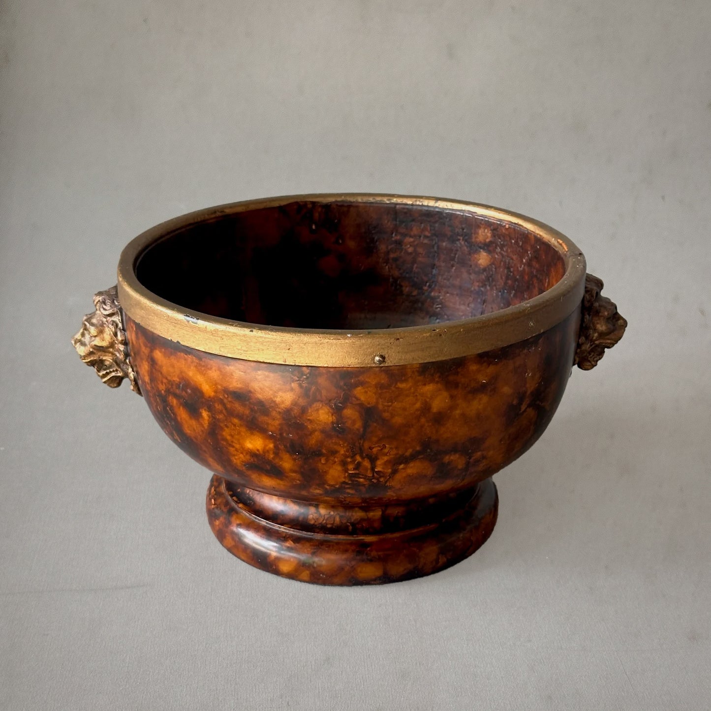 19th-century English faux tortoiseshell bowl with brass rim and lion head handles, front view