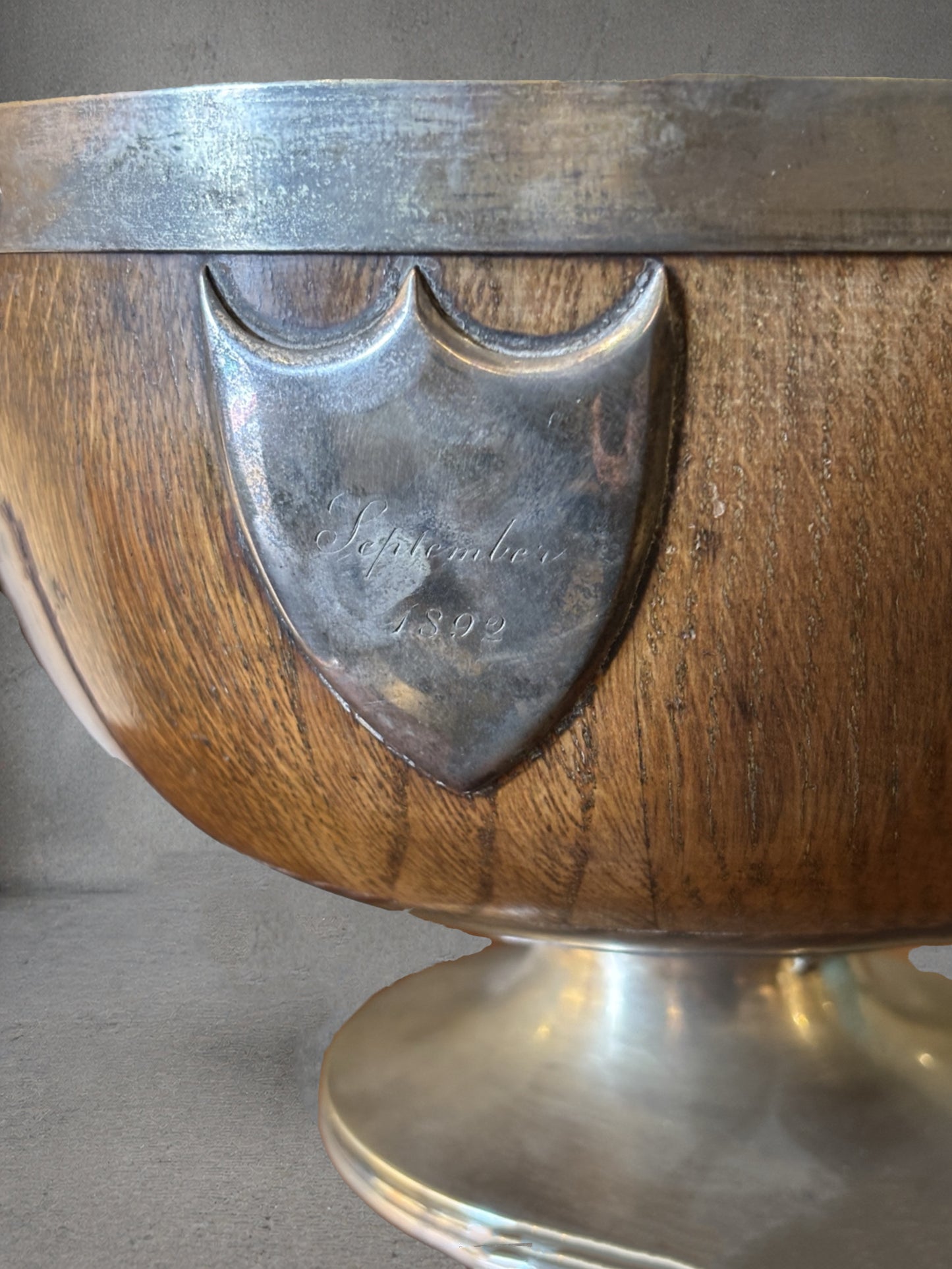 19th century English oak and silver plate wine cooler with lion mask ring handles, engraved September 1892 cartouche, coopered wood body, pedestal base, emblem in front reads september 1892