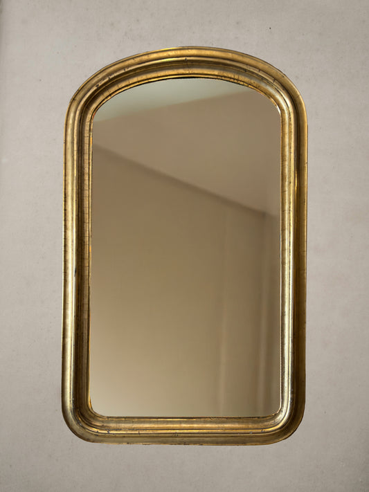 Antique French gilt mirror with rounded corners and original glass, early 20th century, on wall, golden hour