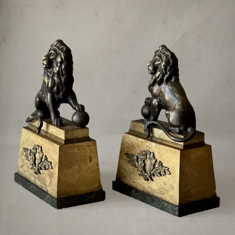 Pair of bronze lion sculptures on faux-painted plinths with laurel wreaths, English neoclassical style, circa 1820, side