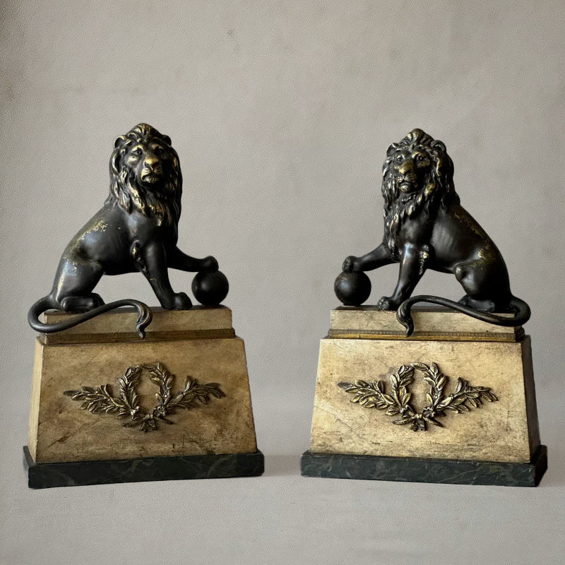 Pair of bronze lion sculptures on faux-painted plinths with laurel wreaths, English neoclassical style, circa 1820