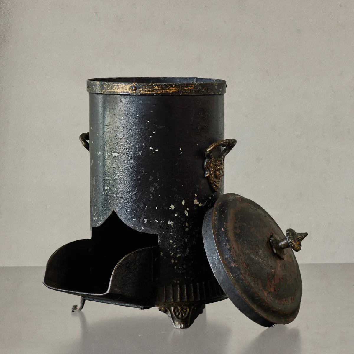 Antique English coal scuttle in black painted tin with finial lid and claw feet, circa 1860