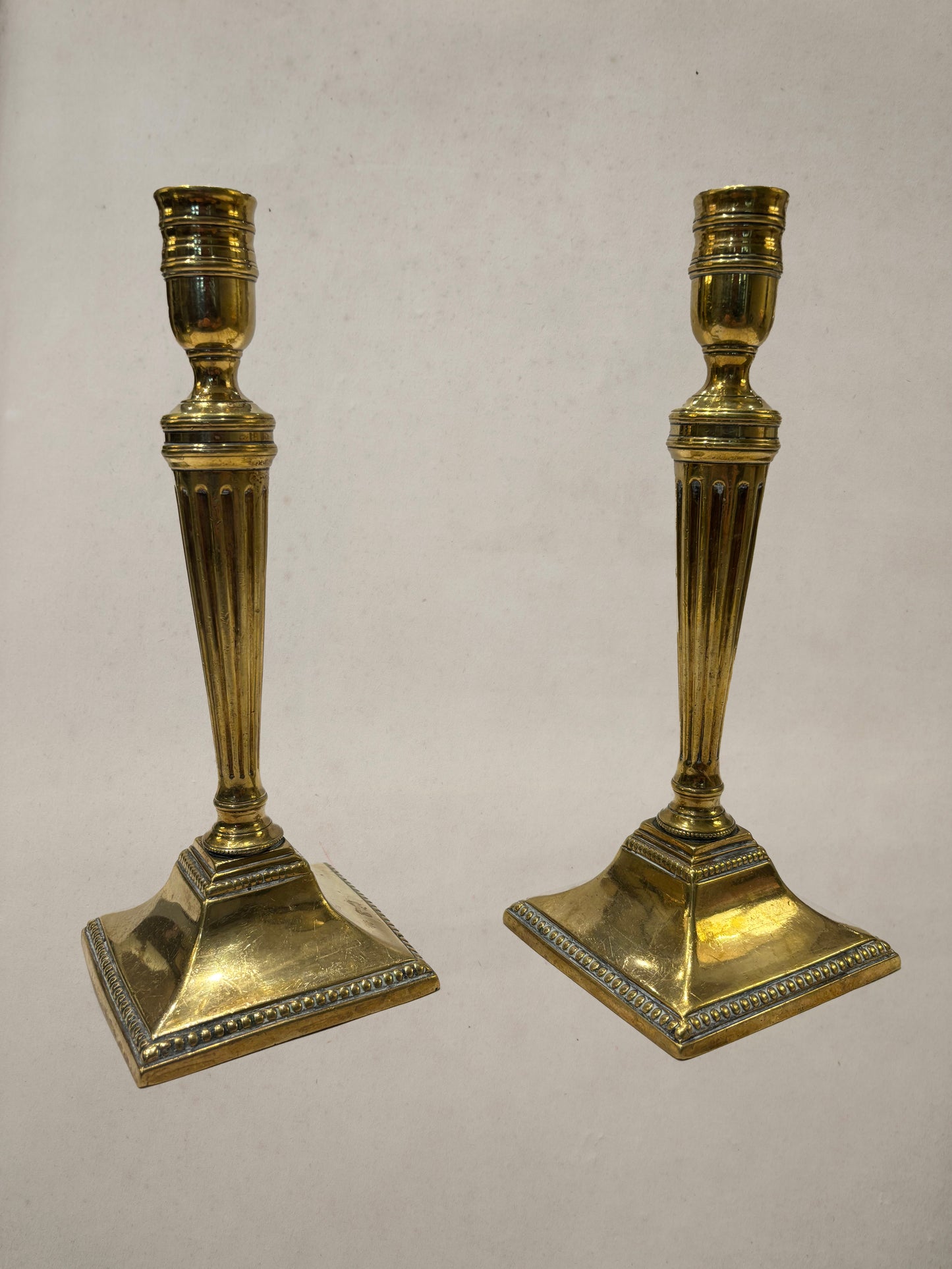 Pair of Georgian brass candlesticks with fluted columns and beaded square bases