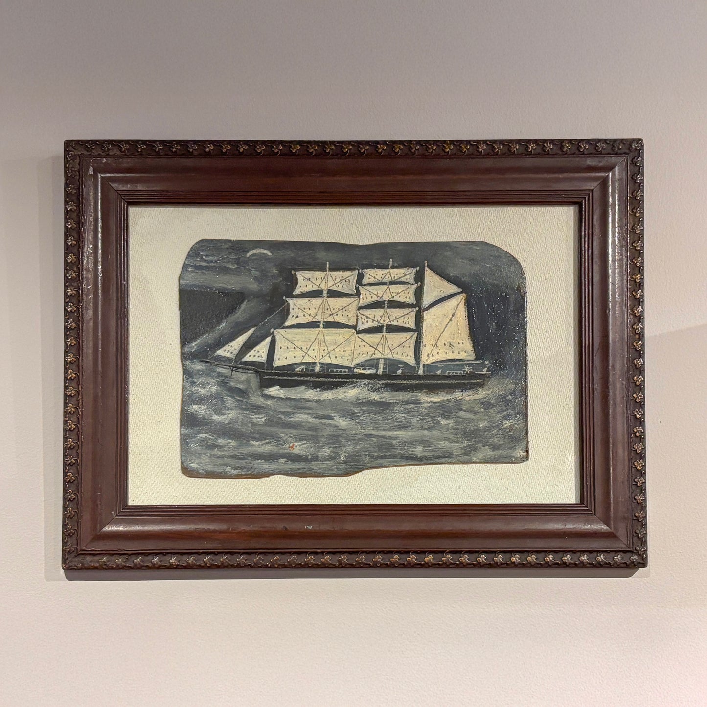 Maritime folk-style painting by Max Wildman showing a sailing ship at sea, framed in dark wood
