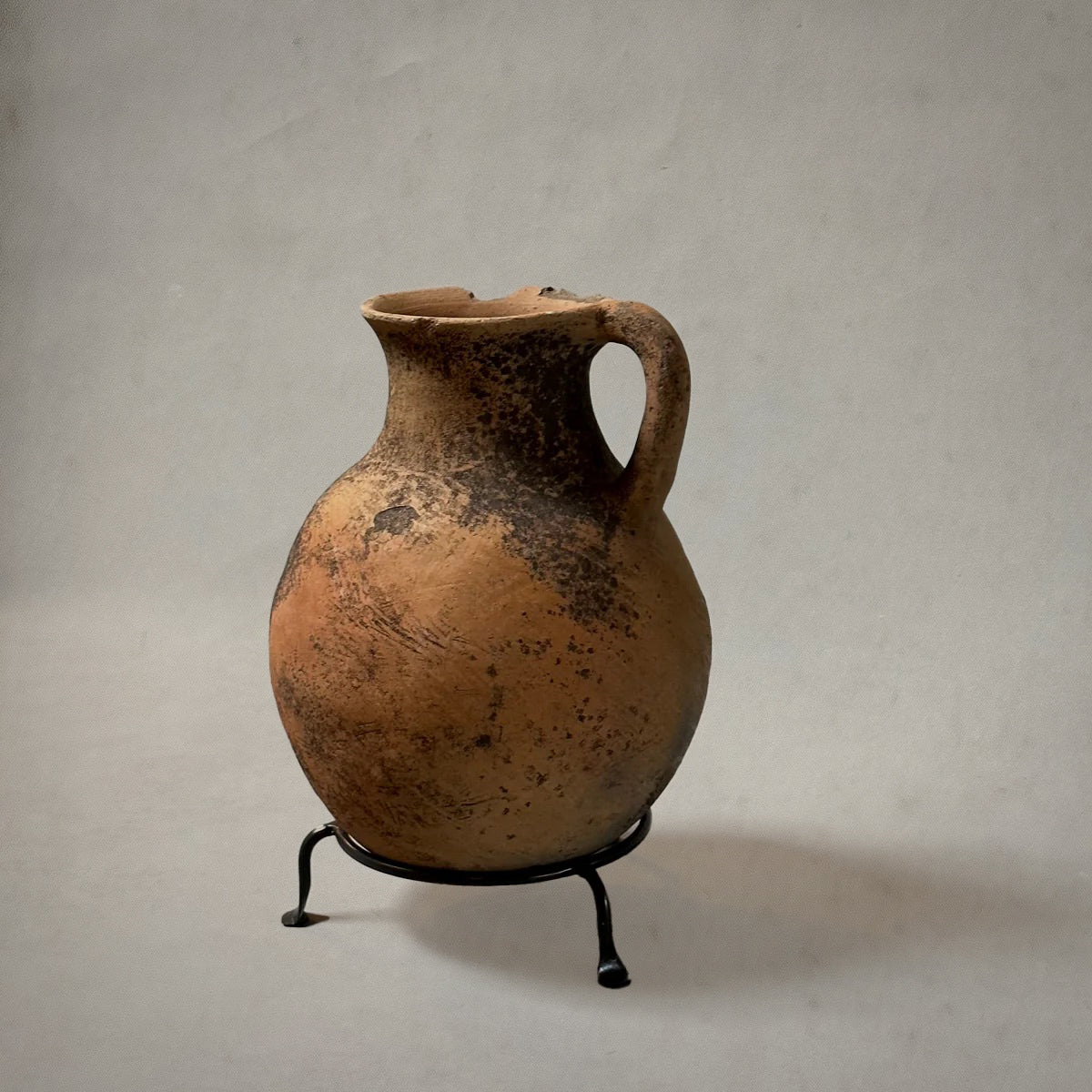 Vintage terra-cotta vessel with handle and mossy patina on metal stand