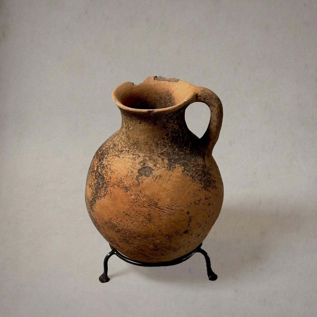 Vintage terra-cotta vessel with handle and mossy patina on metal stand