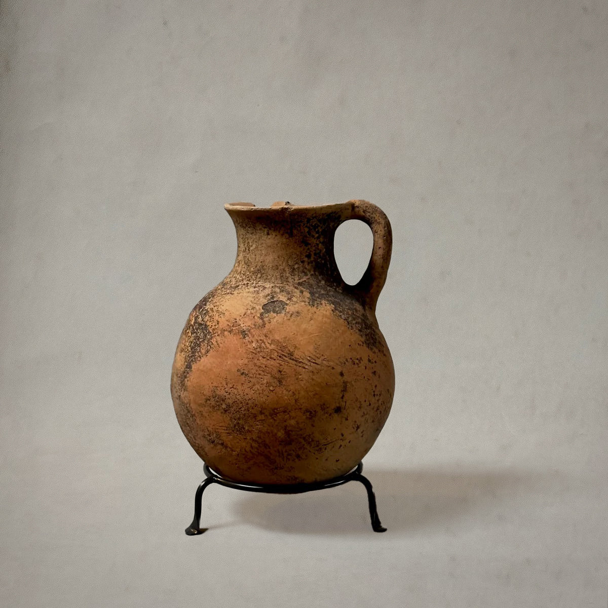 Vintage terra-cotta vessel with handle and mossy patina on metal stand