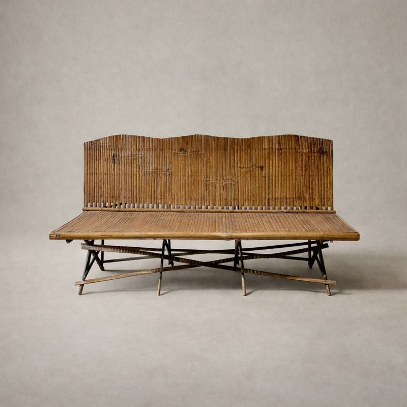 1920s English bamboo bench with slatted back and seat, shown against a soft neutral background, highlighting warm patina and folding base structure.