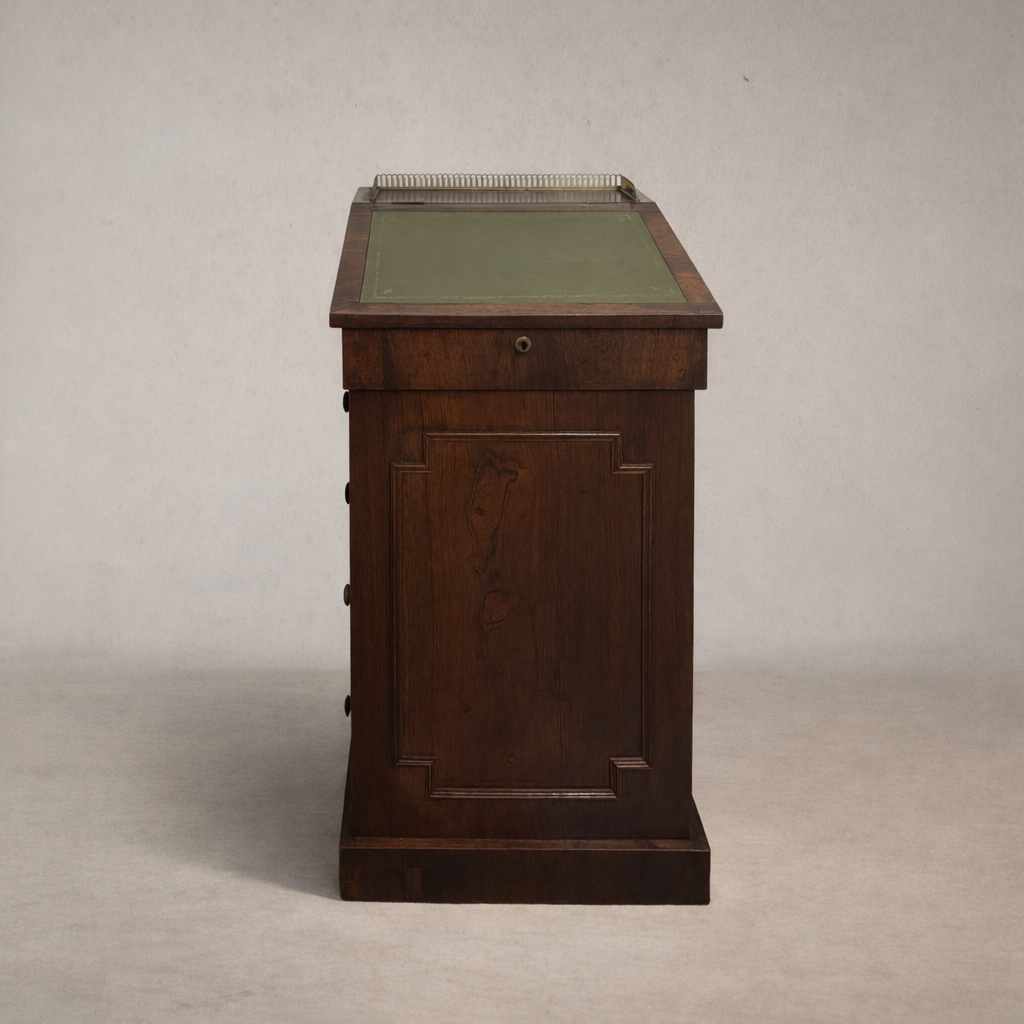 Antique wooden slant-top desk with four drawers, rich patinated wood, and brass details, photographed against a neutral studio background