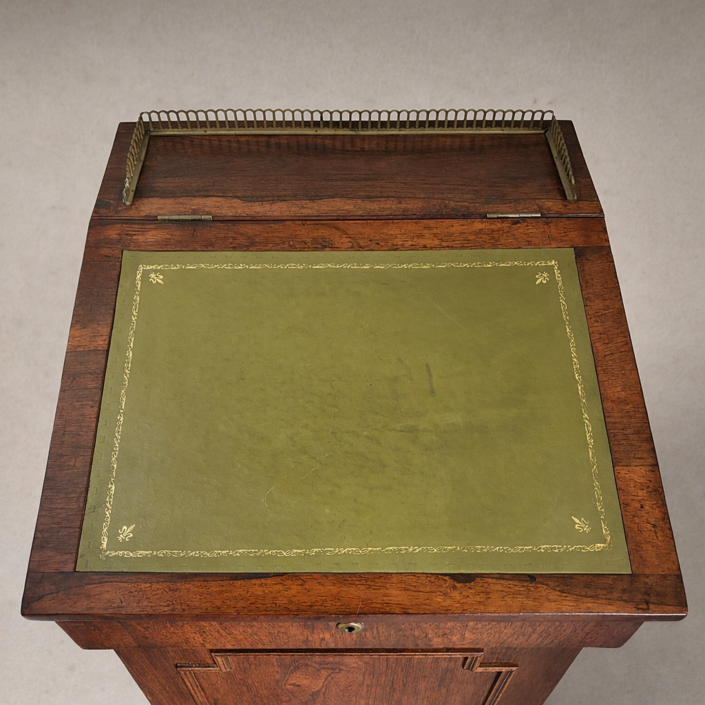 Top view of antique slant-top desk with green leather writing surface and decorative gilt border. Close-up of green leather writing surface with gold tooling on antique wooden desk