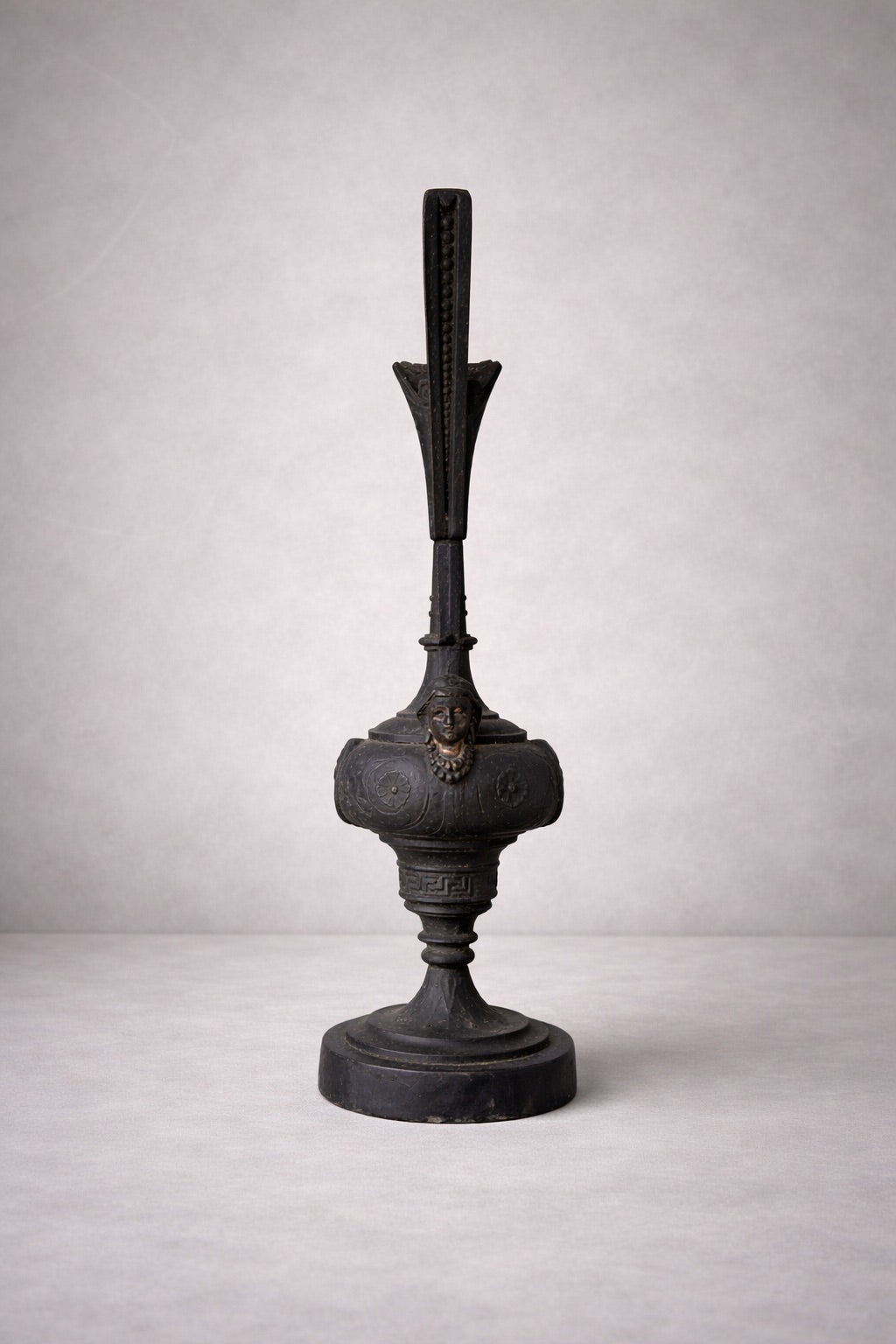 Rear view of neoclassical cast metal ewer showing vertical form, pedestal base, and back detailing on neutral background