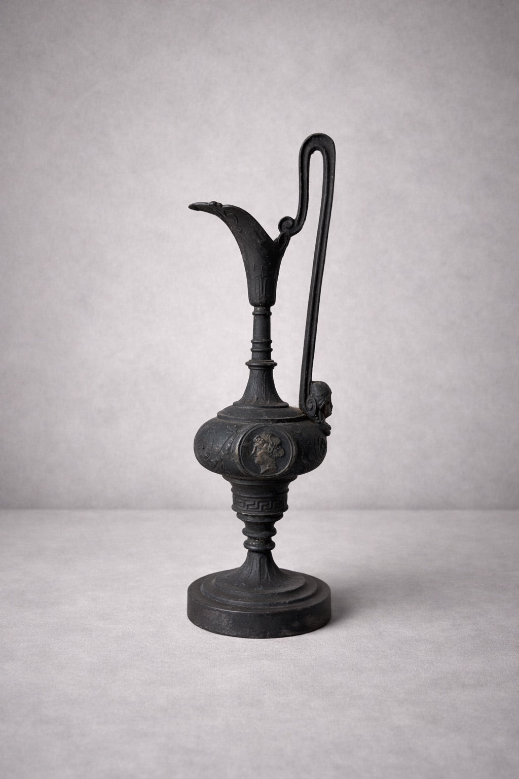 Side view of neoclassical metal ewer showing elongated handle and sculptural spout