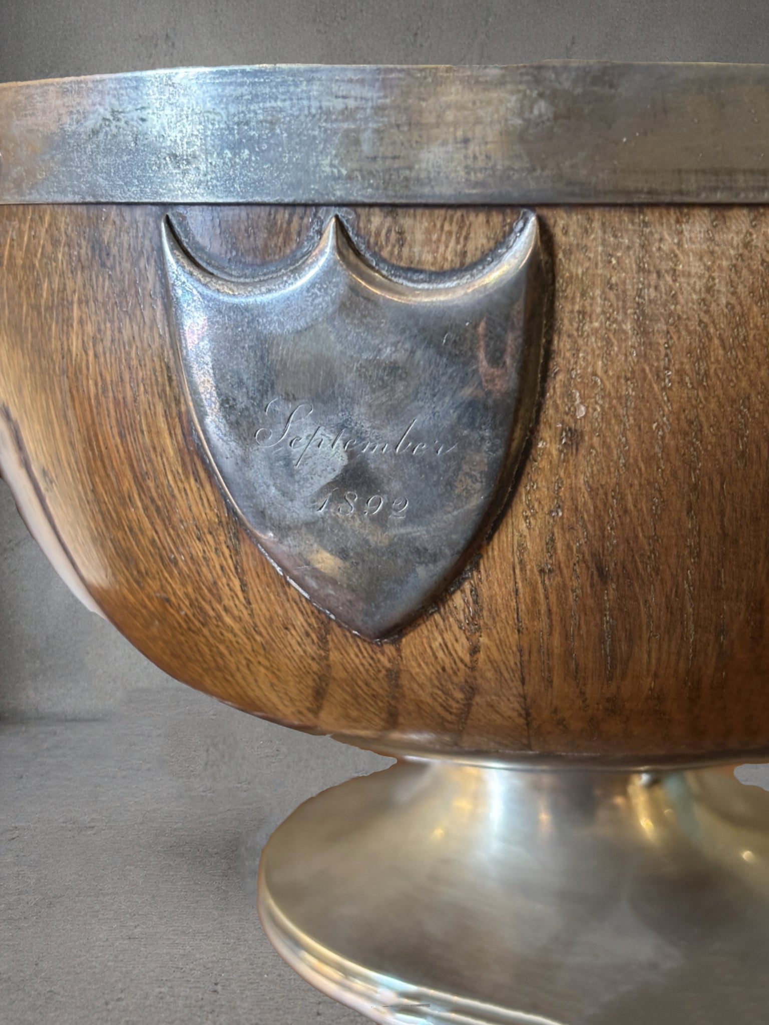 19th century English oak and silver plate wine cooler with lion mask ring handles, engraved September 1892 cartouche, coopered wood body, pedestal base, emblem in front reads september 1892