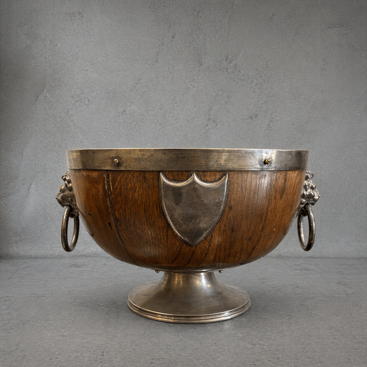 19th century English oak and silver plate wine cooler with lion mask ring handles, engraved September 1892 cartouche, coopered wood body, pedestal base