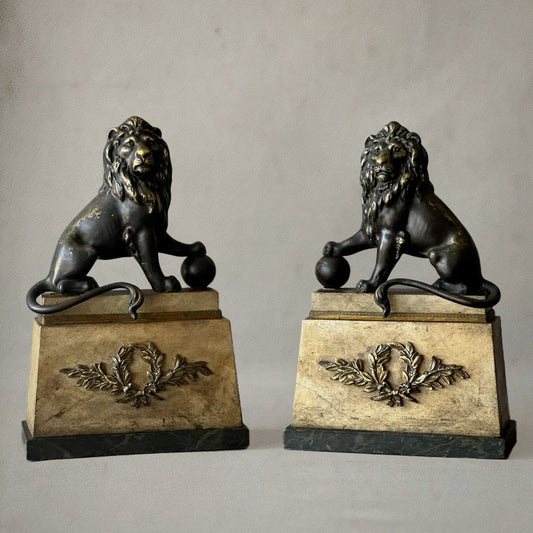 Pair of bronze lion sculptures on faux-painted plinths with laurel wreaths, English neoclassical style, circa 1820