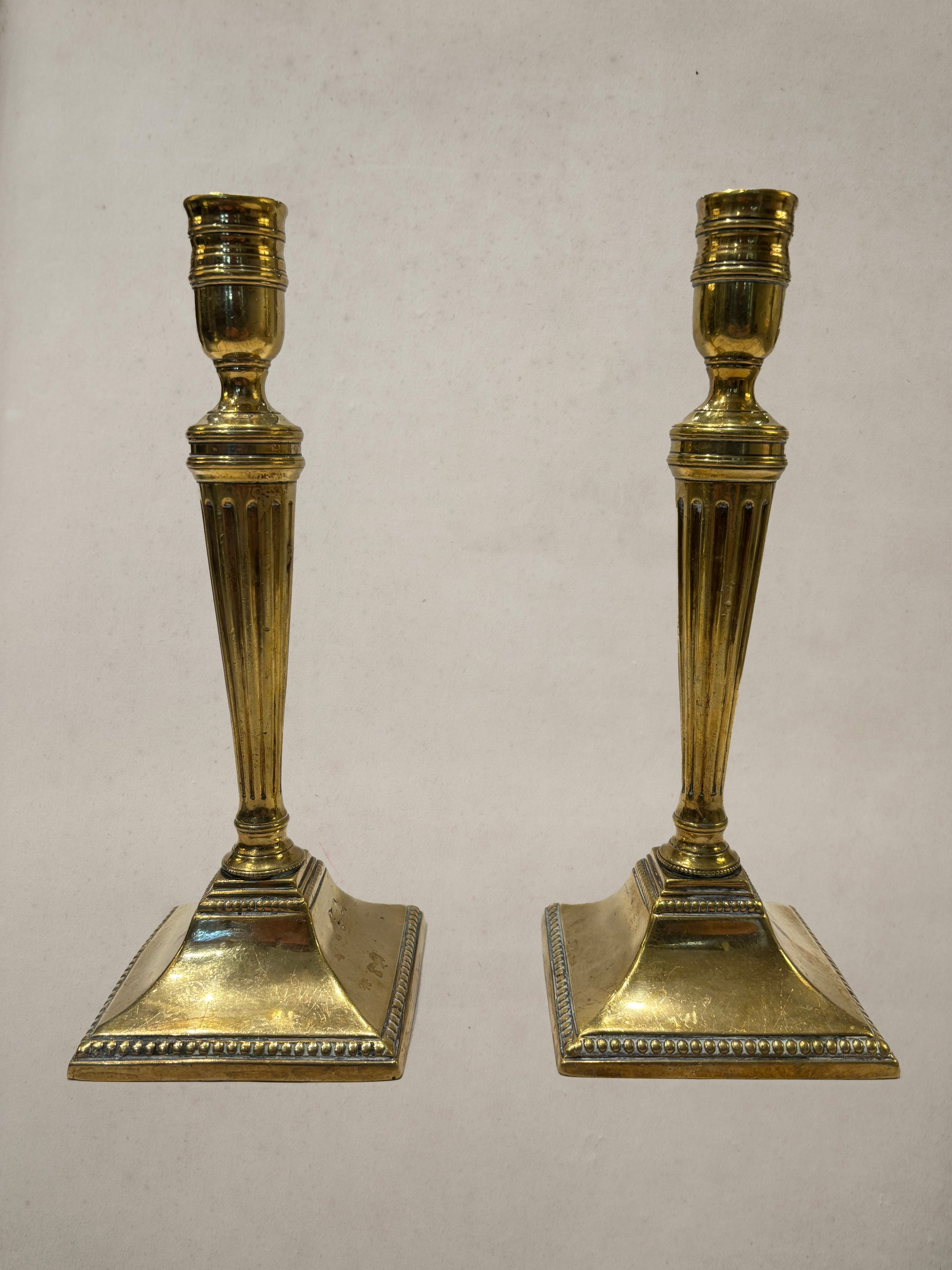 Pair of Georgian brass candlesticks with fluted columns and beaded square bases