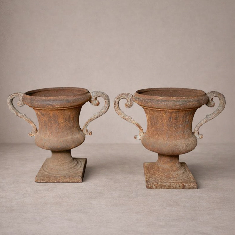 Pair of antique Italian iron urns with scrolled handles and rustic patina