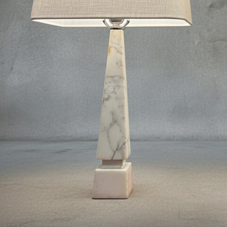 Detail of midcentury Italian white Carrara marble table lamps with geometric bases and ivory linen shades on a neutral textured backdrop
