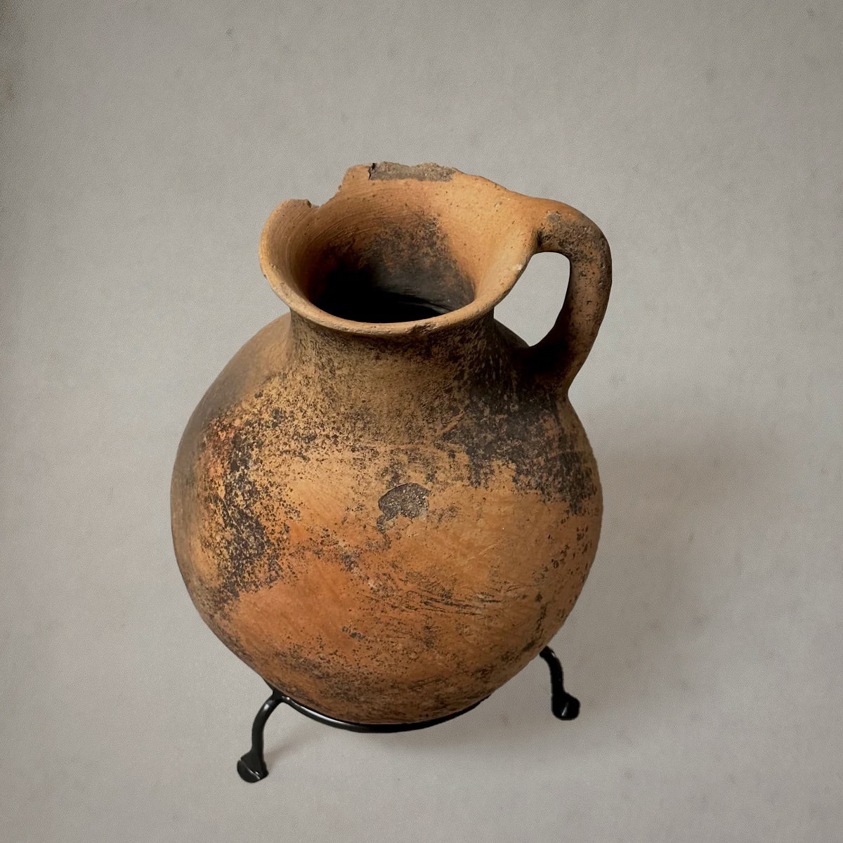 Vintage terra-cotta vessel with handle and mossy patina on metal stand
